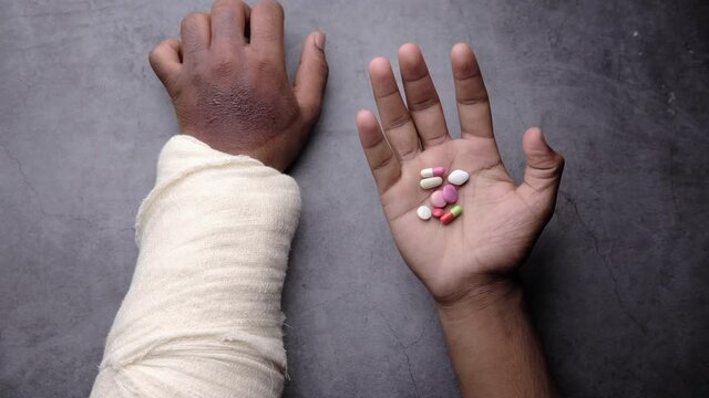 injured painful hand with bandage and medical pills on hand 