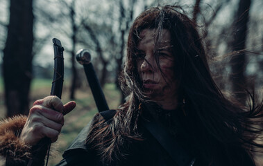 Portrait of woman in image of medieval warrior among forest.