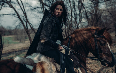 Woman in image of medieval warrior sits horseback.
