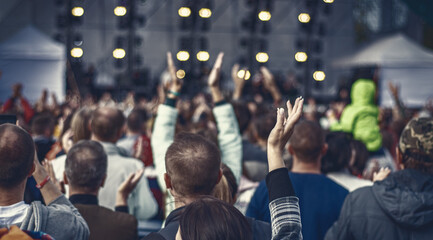 many different people at a concert listening to rock band music open air