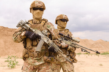 Two equipped and armed special forces soldiers standing in the desert. Concept of military...