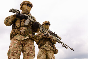 Two special forces soldiers with rifles against sky background, space for text
