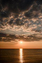 Naklejka na ściany i meble Expanse of the sea against beautiful sunset sky. Sun rays reflected in water.