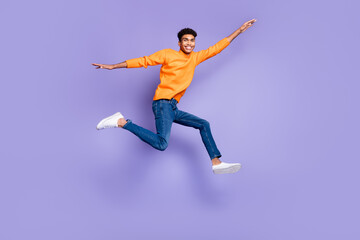 Fototapeta na wymiar Full body photo of brunette afro american man wear jeans go empty space jump isolated on violet color background