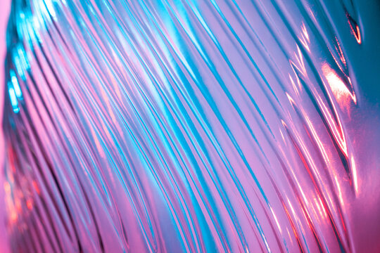 Abstract glass background. Texture of wavy glass illuminated with multi-colored light. Pink and blue stains. glass flares. Close up.