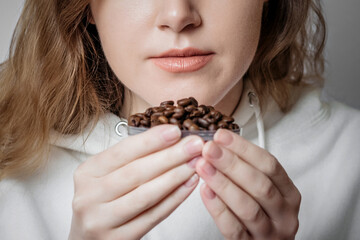 Loss of smell. Close up portrait of caucasian young woman sniffing coffee grains isolated on white background. Coronavirus concept