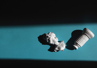 broken replica of an antique bust of a woman lying on the floor in a beam of hard light