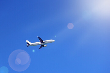 Plane flying high in blue sky with sunny rays