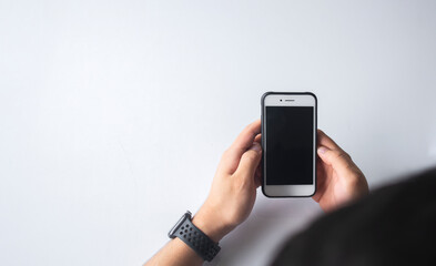 closeup men hand holding texting using mobile relax at home. mockup image blank black screen cell phone. soft-focus and over light in the background