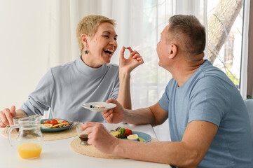 Senior couple enjoys eating healthy breakfast together. Portrait of happy couple