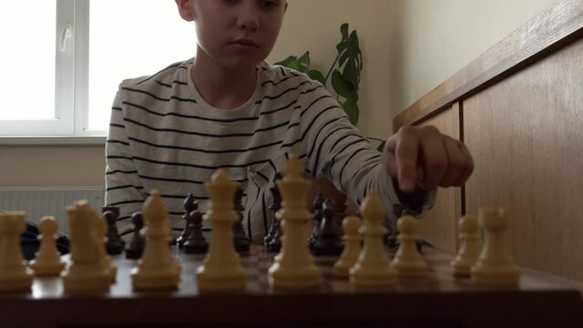 Concentrated boy learning to play chess with digital tablet computer. Education, early development, online learning, entertainment at home