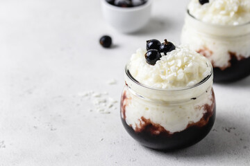 Coconut milk paleo dessrt bluebery compote rice pudding in glass jars. Space for text.