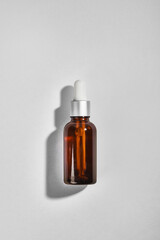 Amber dropper glass bottle on grey background. Mockup