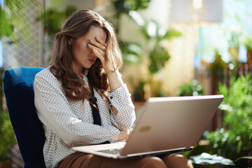stressed trendy woman in sunny day using laptop