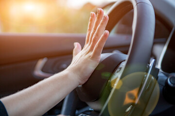hand presses the horn on the steering wheel of a modern car, no face