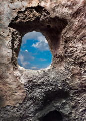 Hole in the wall overlooking the peaceful sky after the war. Stone frame in an old house.