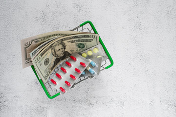 Dollars and pills in a mini grocery basket on a light background, copy space. Conceptual image of buying or selling drugs, healthcare, pharmaceutical business