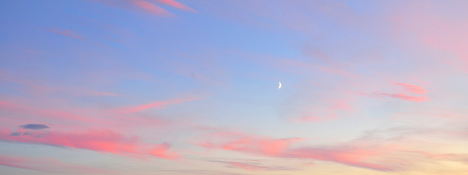 Clear blue sky, glowing pink and golden clouds after storm at sunset. Dramatic cloudscape. Moon, moonrise, midnight sun. Concept art, meteorology, heaven, hope, peace, picturesque panoramic scenery