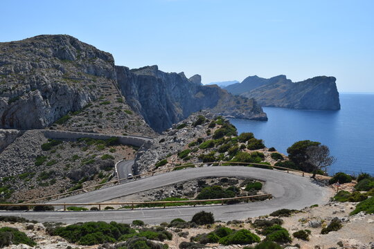 Curvy asphalt road near the coastline in Mallorca, huge cliffs near the ocean, perfect street for motorcycles in a sunny day 