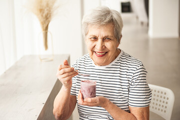 Beautiful old woman eating yogurt. Senior person.  
