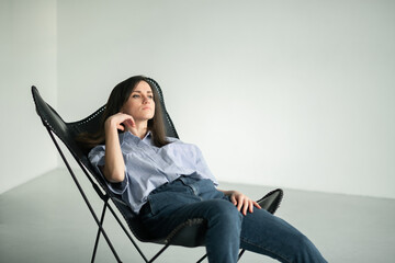 girl resting in a black wrestling
young woman brown eyes black long thick straight hair blue jeans stylish striped blouse, girl sitting at home in a chair relaxed pose