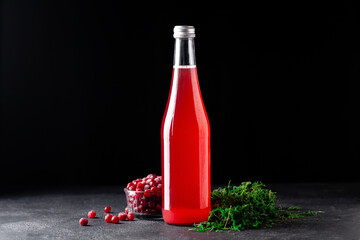 cranberry juice in a glass bottle on a black stone background, cranberry berries, green moss © Анастасия Коровина