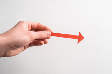 Hand holding a red paper arrow pointing to the right