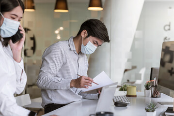 Businessman and businesswoman work together to wear protective masks at the office.