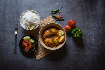 Popular Indian lunch ingredient egg curry in a bowl along with rice and salad condiments. Top view, selective focus. 