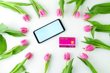 spring flat lay with credit card, tulips and smartphone