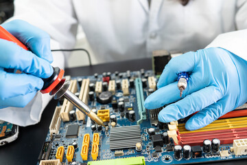 E-waste, technician repairing inside of hard disk by soldering iron. Integrated Circuit. the...