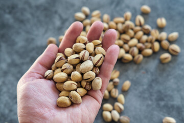 Salted and dried Pistachios in the hand. Blurred stone table as background. Concept of healthy nutrition.