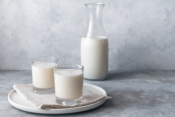 Simple, homemade fermented milk drink-lassi, kefir, yogurt in two glasses on a gray background.