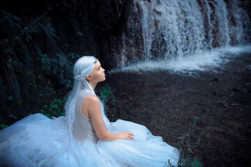 Beautiful portrait of a mysterious ethereal Elf princess sitting Near Waterfall © Elvenphoto
