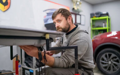 Fototapeta na wymiar Bearded man's car repair service worker, hands photo in work repair process with a car door