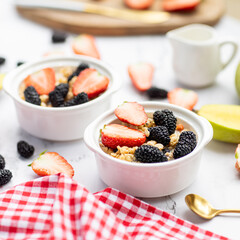 Breakfast oatmeal porridge with fresh fruits and berries, chia seeds on white marble background. Oatmeal with strawberry , mulberry and mango. Healthy breakfast concept. Top view, flat lay, mockup
