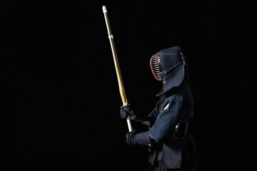 Kendo fighter with with shinai on a black background