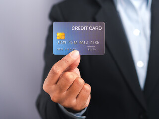 Businessman holding a mockup blue credit card while standing in a studio with copy space for text. Close-up photo. Money and business concept