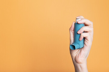 Hand holds inhaler to treat asthma. World Asthma Day. Concept of allergy care. Copy space