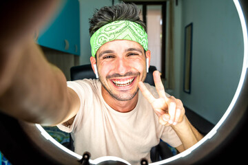 Happy hispanic millennial man making video call at home - Young guy taking a selfie smiling at camera indoor - People, vlog, influencers and dating online concept - obrazy, fototapety, plakaty