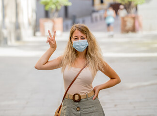 Portrait of attractive young happy woman wearing protective surgical face mask in public spaces