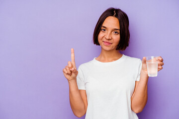 Young mixed race holding a glass of water isolated on purple background showing number one with finger.