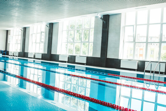 a water pool with blue transparent clear water, on which bright sunlight shines. Water lanes in the swimming pool. indoor sports field for swimming
