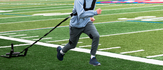 Obraz na płótnie Canvas Runner pulling a sled with weights on a turf field