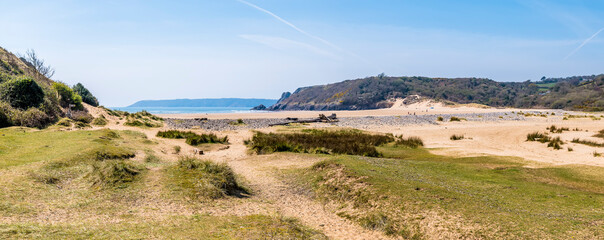A view towards Three Cliffs Bay from the mouth of Pennard Pill, Gower Peninsula, Swansea, South Wales on a sunny day