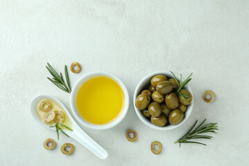Bowls with olives and oil on white textured background