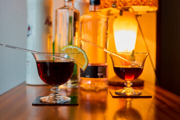 Cocktail glasses with vermouth and lemon, and various bottles