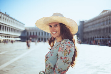 smiling stylish traveller woman in floral dress with hat