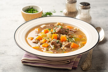 Beef and barley soup with celery, carrot and onion in plate on concrete background - obrazy, fototapety, plakaty