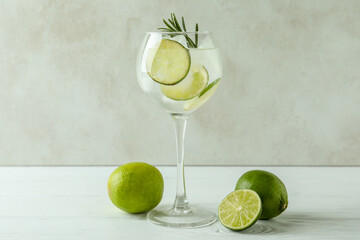 Glass of cocktail with lime on white wooden table